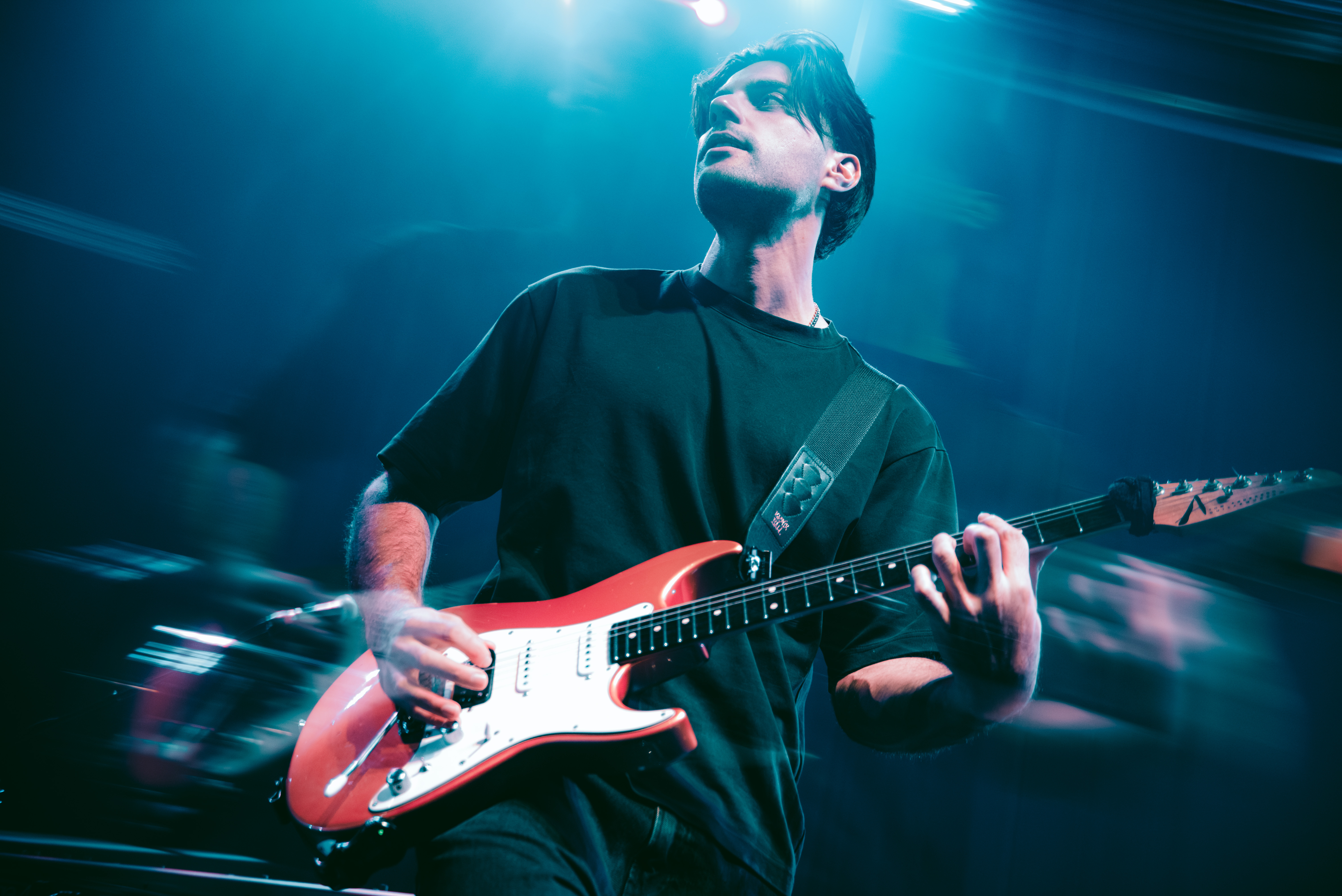 Joe Karakatsanis playing guitar under blue stage lights